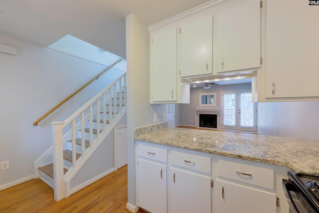 920 Woodrow St Unit 1, Columbia, SC 29205 - kitchen with light wood-type flooring, stove, a fireplace, and white cabinets