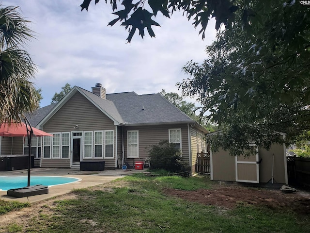 28 Calabash Ln, Elgin, SC 29045 - rear view of house featuring a storage unit, a patio, a chimney, an outdoor pool, and roof with shingles