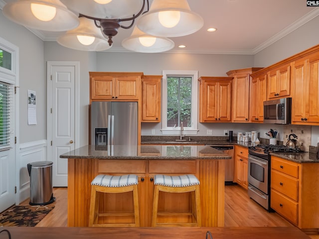 321 Lake Carolina Blvd, Columbia, SC 29229 - kitchen featuring appliances with stainless steel finishes, a sink, light wood-style floors, a center island, and ornamental molding