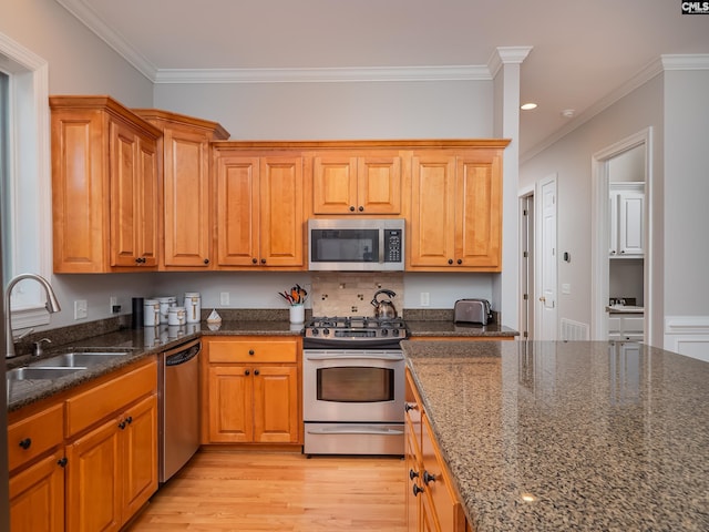 321 Lake Carolina Blvd, Columbia, SC 29229 - kitchen featuring stainless steel appliances, a sink, ornamental molding, dark stone countertops, and light wood-style floors