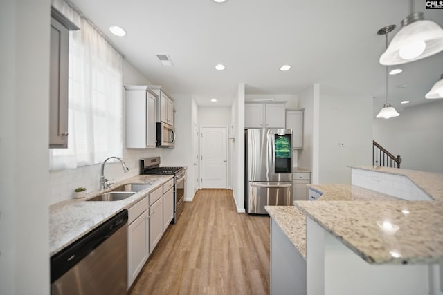 514 Red Taffy Way, Lexington, SC 29073 - kitchen featuring stainless steel appliances, a sink, light wood-style floors, backsplash, and hanging light fixtures
