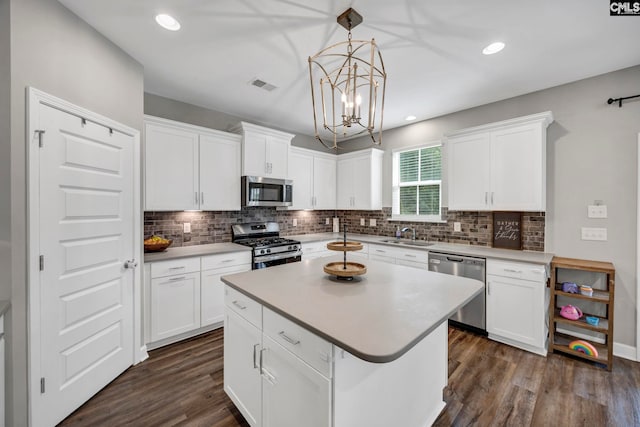556 Harbour Pointe Dr, Columbia, SC 29229 - kitchen featuring appliances with stainless steel finishes, tasteful backsplash, dark wood-style flooring, white cabinets, and a chandelier