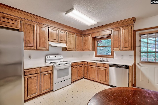 519 Cockspur Rd, Irmo, SC 29063 - kitchen with appliances with stainless steel finishes, under cabinet range hood, a sink, brown cabinetry, and a textured ceiling