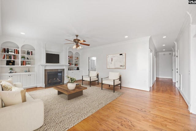 104 Eastshore Dr, Lexington, SC 29072 - living room with crown molding, a ceiling fan, a tile fireplace, built in features, and light wood-type flooring