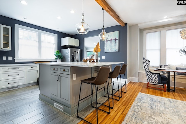 2808 River Dr, Columbia, SC 29201 - kitchen featuring stainless steel fridge with ice dispenser, light wood-style flooring, a kitchen bar, an island with sink, and hanging light fixtures