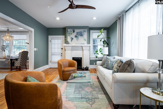2808 River Dr, Columbia, SC 29201 - living area featuring wood finished floors, a ceiling fan, baseboards, a fireplace, and a chandelier