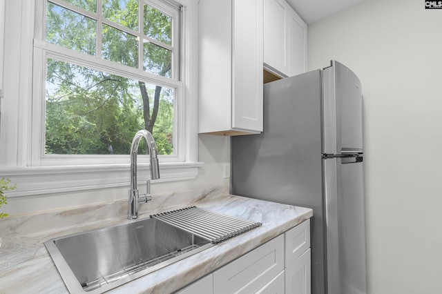 2611 Mills Dr, Columbia, SC 29204 - kitchen featuring a sink, white cabinets, freestanding refrigerator, and light stone counters