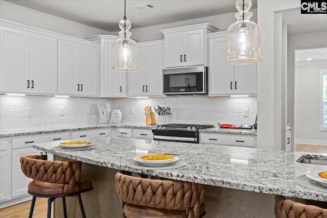 521 Fenwick Dr, Woodruff, SC 29388 - kitchen featuring appliances with stainless steel finishes, a breakfast bar area, white cabinets, and light wood-type flooring