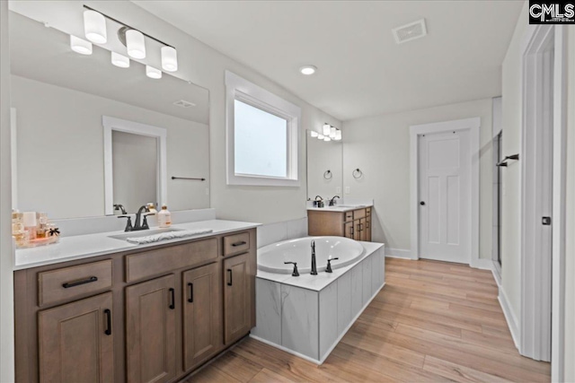 521 Fenwick Dr, Woodruff, SC 29388 - bathroom featuring two vanities, a garden tub, wood finished floors, and a shower