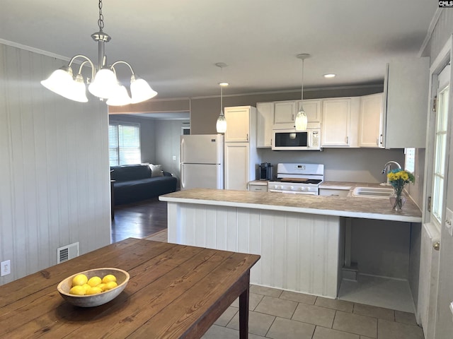 1432 Karlaney Ave, Cayce, SC 29033 - kitchen with white appliances, a peninsula, light countertops, a chandelier, and white cabinets