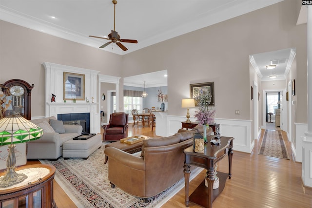 317 Cartgate Cir, Blythewood, SC 29016 - living room featuring crown molding, a ceiling fan, light wood-style flooring, a wainscoted wall, and a tiled fireplace