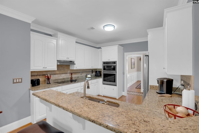 317 Cartgate Cir, Blythewood, SC 29016 - kitchen with a sink, under cabinet range hood, stainless steel double oven, black electric cooktop, and a peninsula