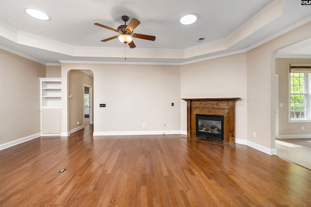 560 Park Place Dr, Elgin, SC 29045 - unfurnished living room featuring arched walkways, ceiling fan, wood finished floors, a tray ceiling, and crown molding