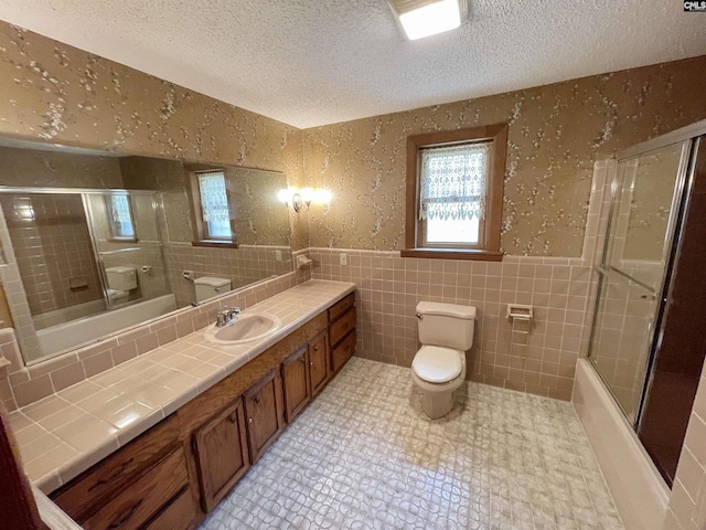 325 Beltline Ave, Batesburg, SC 29006 - full bathroom featuring toilet, a textured ceiling, tile walls, vanity, and combined bath / shower with glass door