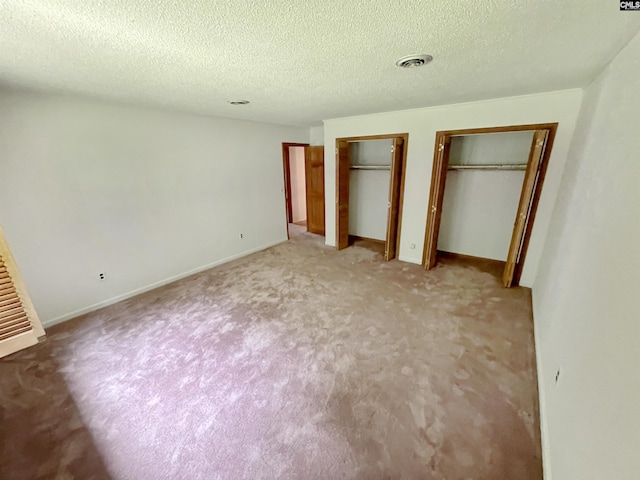 325 Beltline Ave, Batesburg, SC 29006 - unfurnished bedroom featuring multiple closets, light colored carpet, a textured ceiling, and baseboards
