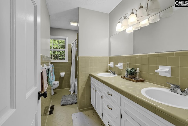 1305 Forest View Rd, Conway, SC 29526 - full bathroom featuring tile walls, toilet, double vanity, wainscoting, and tile patterned flooring
