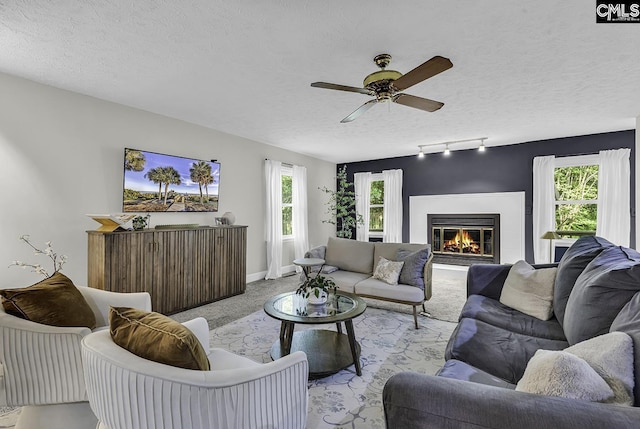 1305 Forest View Rd, Conway, SC 29526 - carpeted living room with a textured ceiling, a ceiling fan, a glass covered fireplace, baseboards, and rail lighting