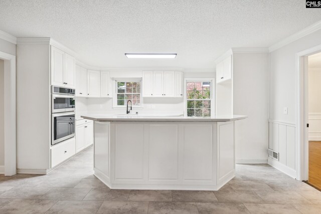 6307 Whiteoak Rd, Columbia, SC 29206 - kitchen with double oven, plenty of natural light, white cabinetry, ornamental molding, and light countertops