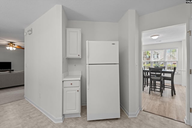 125 Oak Cove Dr, Columbia, SC 29229 - kitchen with freestanding refrigerator, ceiling fan, baseboards, white cabinets, and a textured ceiling