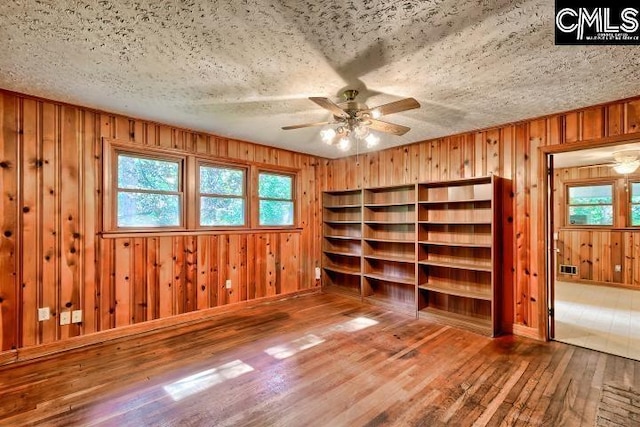 127 Lake Elizabeth Dr, Columbia, SC 29203 - spare room featuring wood-type flooring, a ceiling fan, plenty of natural light, wood walls, and a textured ceiling