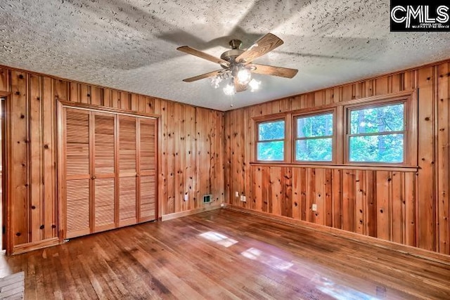 127 Lake Elizabeth Dr, Columbia, SC 29203 - unfurnished bedroom with wood-type flooring, wood walls, a textured ceiling, a closet, and ceiling fan