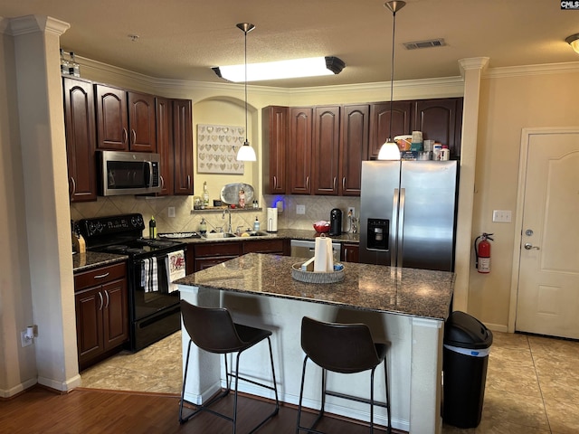 1085 Shop Rd Unit 117, Columbia, SC 29201 - kitchen featuring appliances with stainless steel finishes, a kitchen breakfast bar, backsplash, dark brown cabinetry, and crown molding