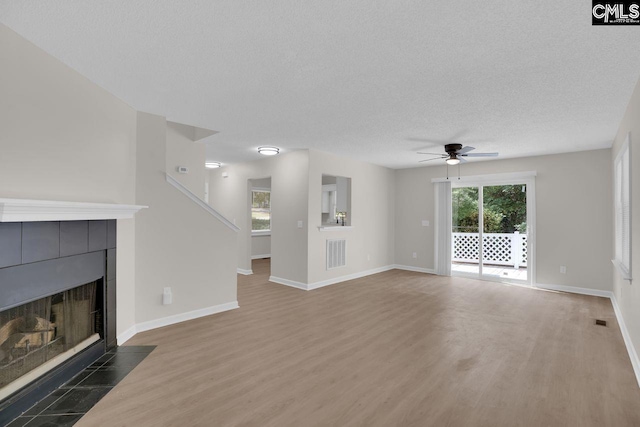 204 Sandcreek Dr, Winnsboro, SC 29180 - unfurnished living room with wood finished floors, ceiling fan, a tiled fireplace, a textured ceiling, and baseboards