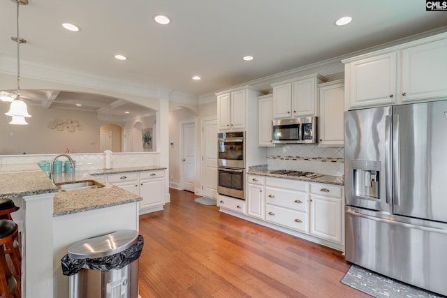 535 New Cut Ln, Blythewood, SC 29016 - kitchen featuring appliances with stainless steel finishes, arched walkways, a sink, light wood-style flooring, and white cabinets