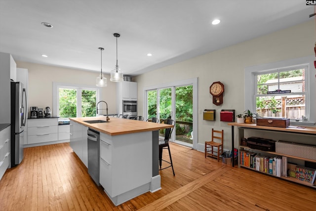 107 Southwood, Columbia, SC 29205 - kitchen with modern cabinets, stainless steel appliances, butcher block countertops, white cabinets, and an island with sink
