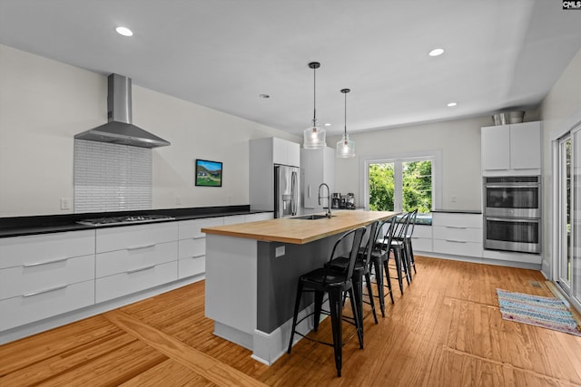 107 Southwood, Columbia, SC 29205 - kitchen with wall chimney exhaust hood, wood counters, modern cabinets, appliances with stainless steel finishes, and white cabinetry