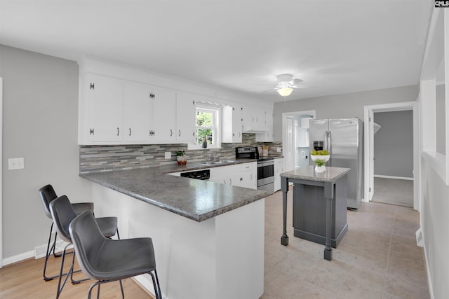 344 Rawls Dr, Leesville, SC 29070 - kitchen featuring appliances with stainless steel finishes, decorative backsplash, a kitchen bar, ceiling fan, and dark countertops