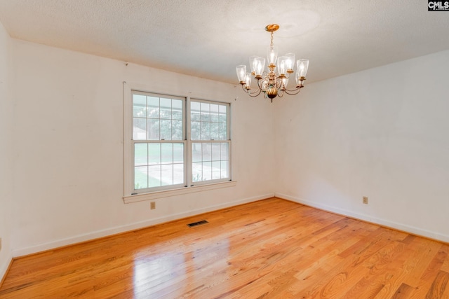 2117 Togetherness Way, Mcbee, SC 29101 - empty room with light wood-style flooring, a chandelier, and a textured ceiling