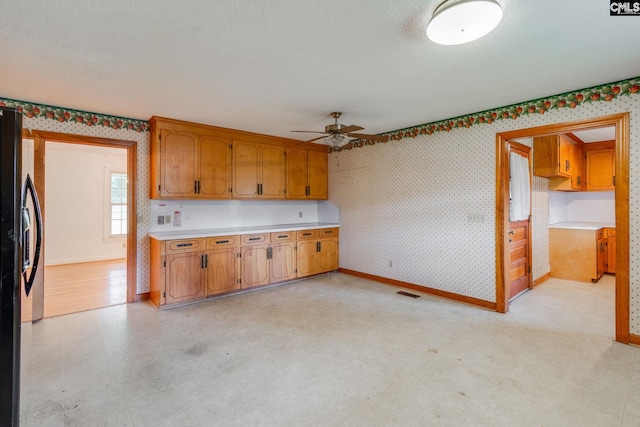 2117 Togetherness Way, Mcbee, SC 29101 - kitchen featuring a ceiling fan, light countertops, wallpapered walls, fridge with ice dispenser, and brown cabinets