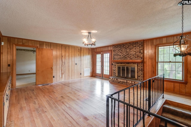 2117 Togetherness Way, Mcbee, SC 29101 - unfurnished living room with a chandelier, a textured ceiling, healthy amount of natural light, wood walls, and wood finished floors