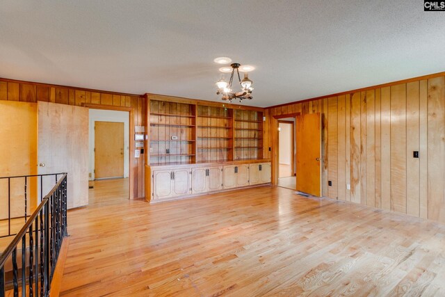2117 Togetherness Way, Mcbee, SC 29101 - empty room with wood walls, a chandelier, light wood-style flooring, a textured ceiling, and ornamental molding