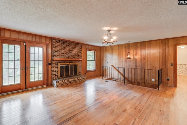 2117 Togetherness Way, Mcbee, SC 29101 - unfurnished living room with a chandelier, wood finished floors, wooden walls, a textured ceiling, and a brick fireplace