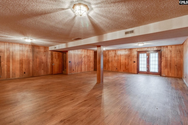 2117 Togetherness Way, Mcbee, SC 29101 - basement featuring wood walls, light wood-style flooring, a textured ceiling, and french doors