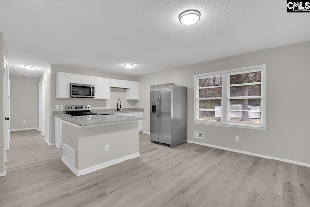 112 Woodcrest Dr, Columbia, SC 29203 - kitchen featuring appliances with stainless steel finishes, light wood-type flooring, white cabinets, a kitchen island, and a textured ceiling