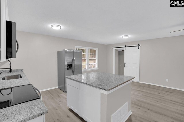 112 Woodcrest Dr, Columbia, SC 29203 - kitchen featuring appliances with stainless steel finishes, a barn door, light wood-style flooring, white cabinets, and a center island