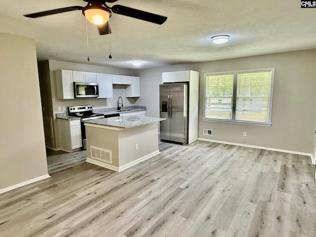 112 Woodcrest Dr, Columbia, SC 29203 - kitchen with stainless steel appliances, light wood-style floors, white cabinetry, and a center island