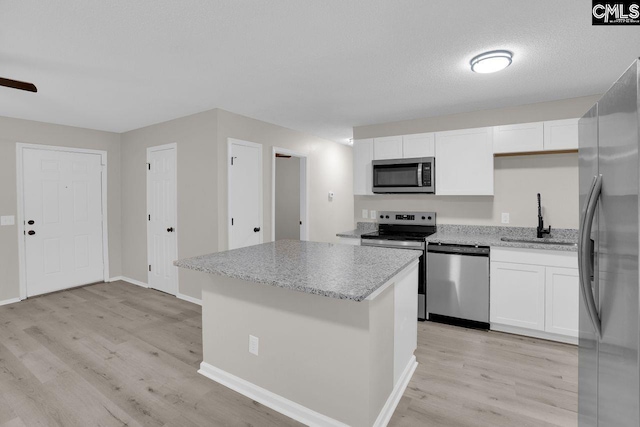 112 Woodcrest Dr, Columbia, SC 29203 - kitchen with appliances with stainless steel finishes, light wood-style floors, a kitchen island, white cabinetry, and light stone counters