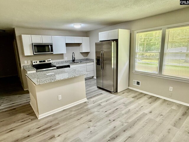 112 Woodcrest Dr, Columbia, SC 29203 - kitchen with appliances with stainless steel finishes, light wood-style flooring, white cabinets, light stone countertops, and a textured ceiling