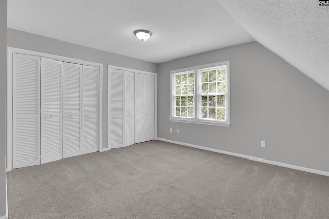 325 Trinity Three Rd, Irmo, SC 29063 - unfurnished bedroom featuring multiple closets, a textured ceiling, carpet flooring, and vaulted ceiling