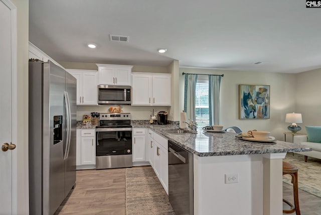126B Willow Creek Blvd, Lugoff, SC 29078 - kitchen with stainless steel appliances, a peninsula, a breakfast bar, white cabinets, and stone counters