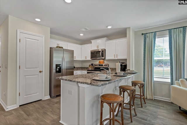 126B Willow Creek Blvd, Lugoff, SC 29078 - kitchen featuring stainless steel appliances, a peninsula, wood finished floors, white cabinets, and recessed lighting