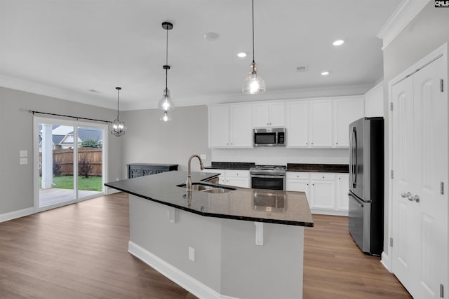 935 Taramore Ln, Lexington, SC 29072 - kitchen with appliances with stainless steel finishes, ornamental molding, decorative backsplash, light wood-style floors, and a center island with sink