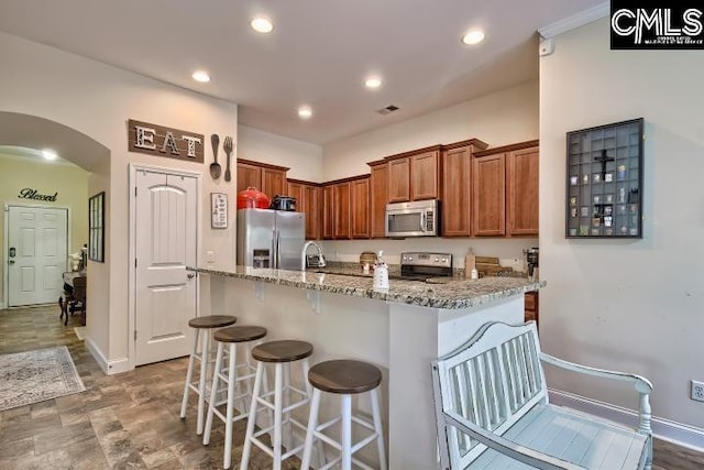 1817 Crystal Ln, West Columbia, SC 29170 - kitchen featuring stainless steel appliances, arched walkways, light stone counters, a kitchen bar, and recessed lighting