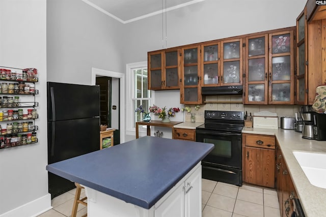 1208 Peacehaven Rd, Chapin, SC 29036 - kitchen featuring black appliances, light tile patterned floors, under cabinet range hood, brown cabinetry, and glass insert cabinets