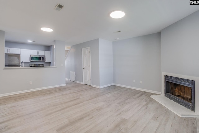 1320 Piney Grove Rd Unit 3C, Columbia, SC 29210 - unfurnished living room featuring light wood-type flooring and a fireplace with raised hearth