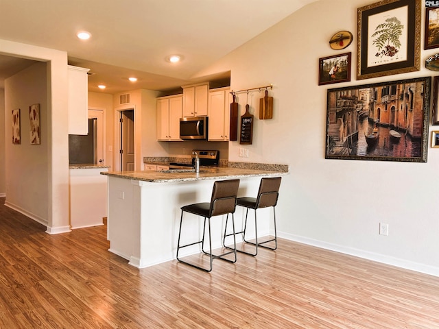 1406 Native Garden Rd, Gilbert, SC 29054 - kitchen featuring appliances with stainless steel finishes, a peninsula, light wood-style floors, a breakfast bar area, and recessed lighting